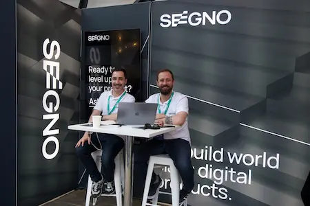 Two people at a sponsor stand pose for a photo.