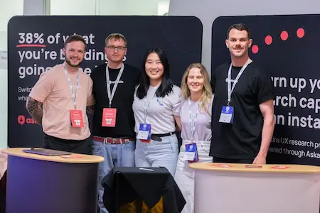 A group of five people at a sponsor stand pose for a photo.