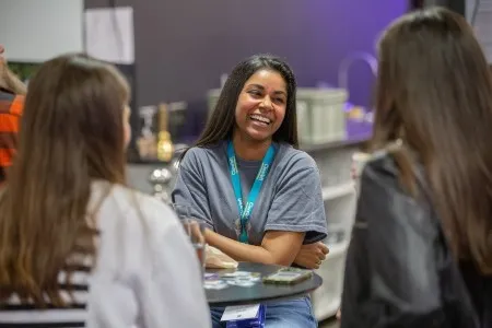 A woman laughing as she chats with other attendees during a break.