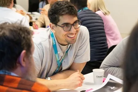 A woman smiling as she goes from table to table during her workshop.