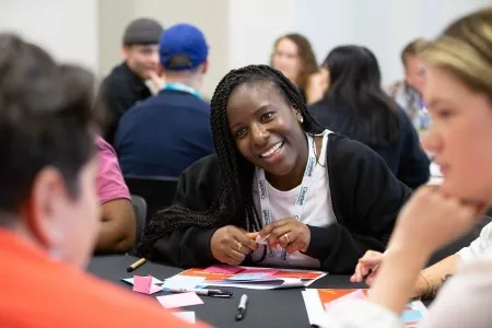 A workshop attendee smiling and leaning in during a group exercise.