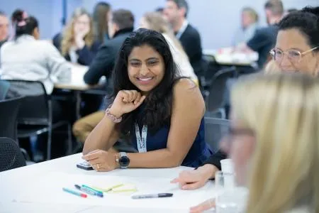 A workshop attendee smiling and listening during a group exercise.