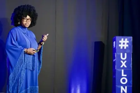 A woman dressed in blue on stage at UX London.