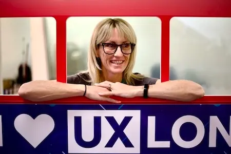 A smiling woman looks out of a mockup of a London bus branded for UX London.