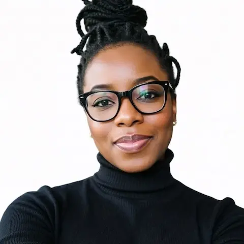 Portrait of a woman dressed in black wearing glasses with her hair tied up.