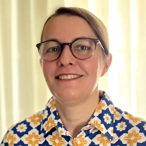 A woman wearing glasses and a colourful floral shirt.